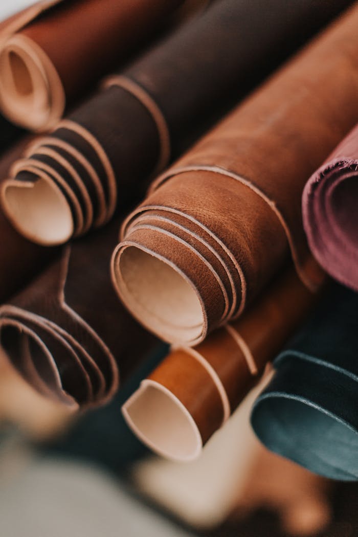 about-bg A detailed close-up of various rolled brown leather pieces, highlighting textures.